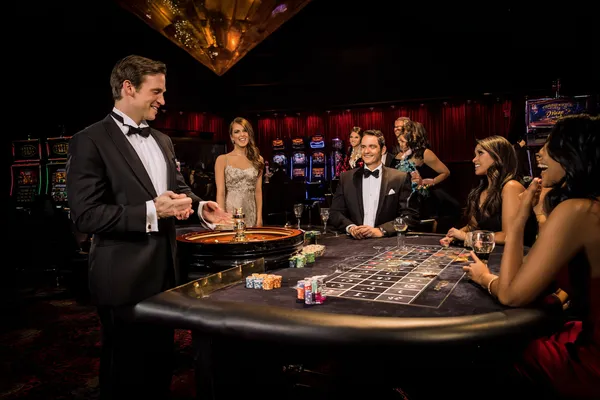 A professional dealer in a tuxedo greeting players at the roulette table, symbolizing the authentic live casino feel at JEETA.